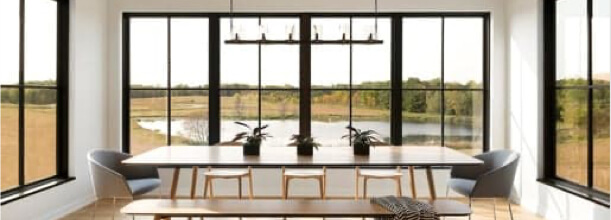 Dining area surrounded by large black windows with grilles